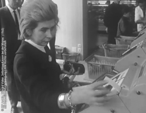 Kundin entnimmt 1965 den Kassenbon an einer historischen Selbsttipp-Kasse der Migros.